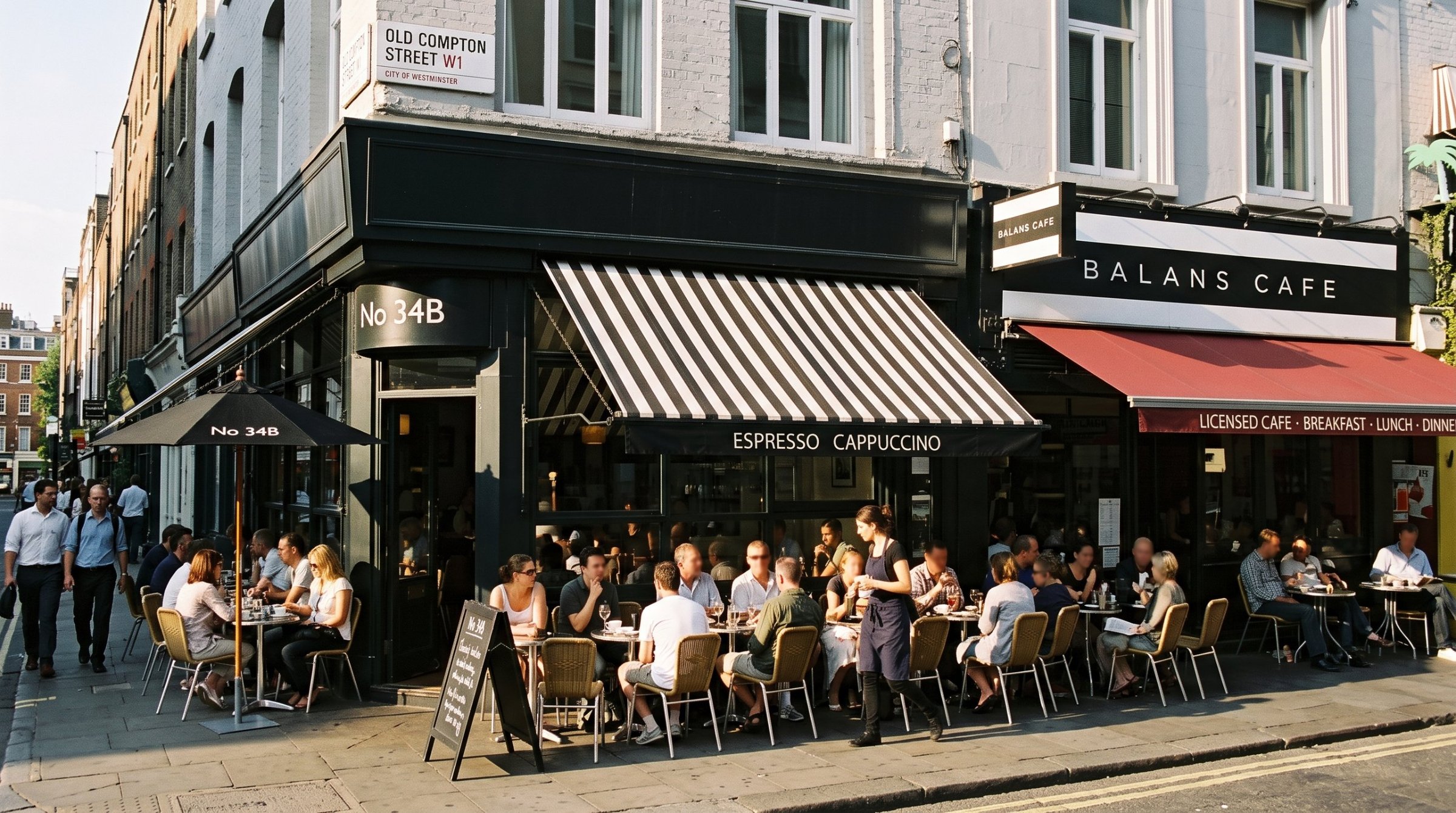 Pavement tables full outside 34b and Balans Cafe on Old Compton Street.